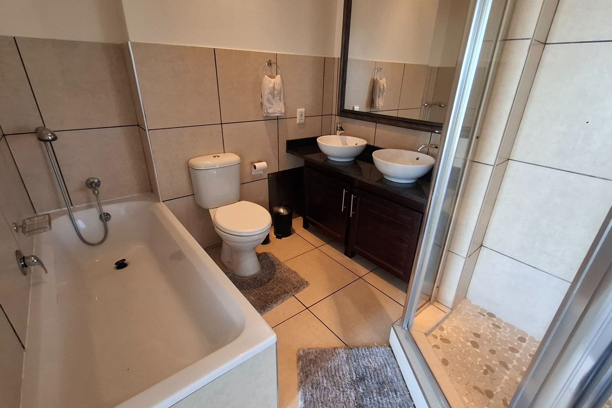 A well-appointed bathroom featuring a double vanity with vessel sinks, a separate bathtub, and a glass-enclosed shower with tiled finishes.