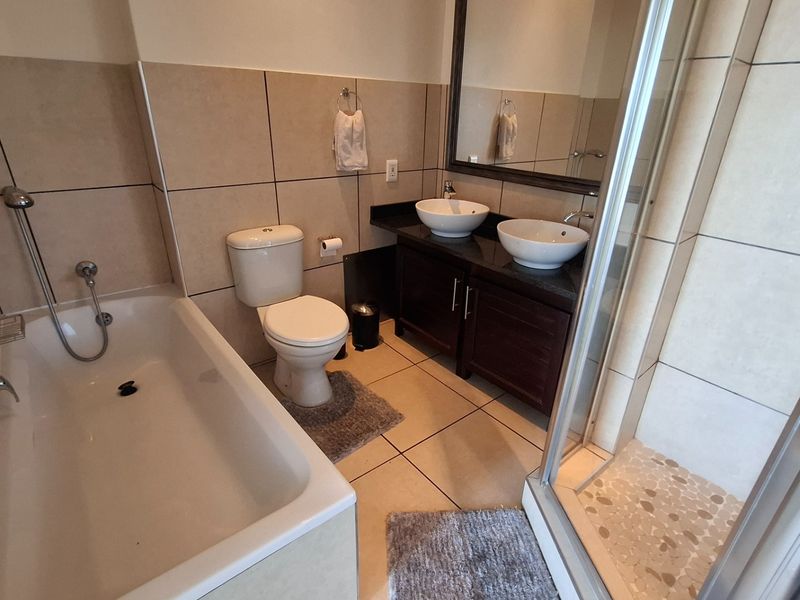A well-appointed bathroom featuring a double vanity with vessel sinks, a separate bathtub, and a glass-enclosed shower with tiled finishes.