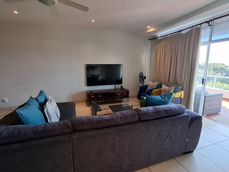 Spacious living room featuring tiled flooring, recessed lighting, a ceiling fan, and direct access to a balcony through large sliding glass doors.