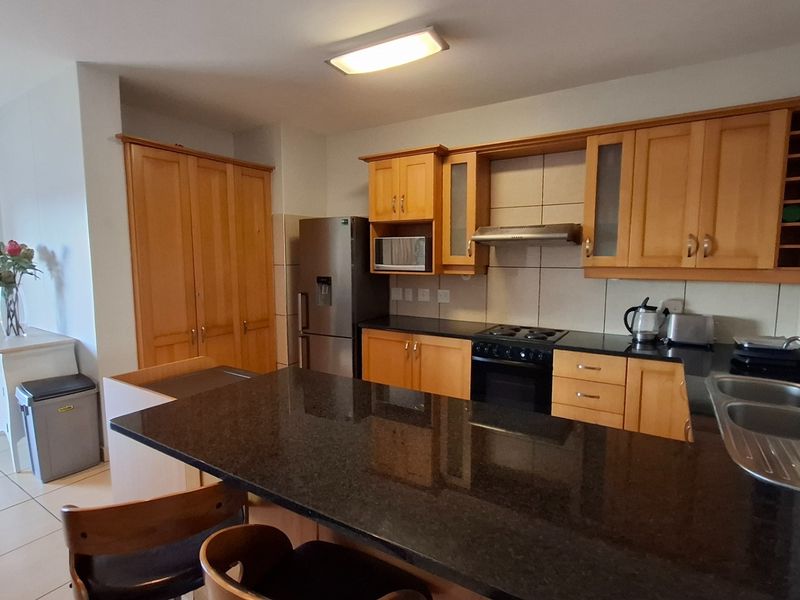 A functional kitchen featuring wooden cabinetry, granite countertops, a built-in oven with extractor fan, and a breakfast bar island.