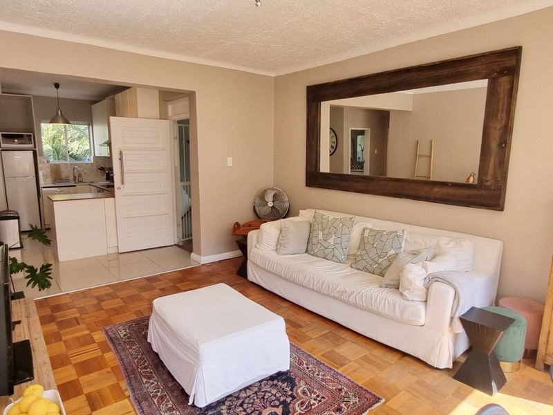 Open plan living area featuring parquet flooring, flowing into a functional kitchen with built-in cabinetry and appliances.