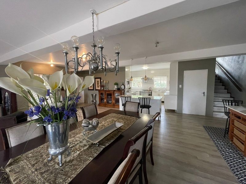 Spacious open-plan living and dining area featuring modern laminate flooring, a central kitchen island, and a staircase leading to the upper level.