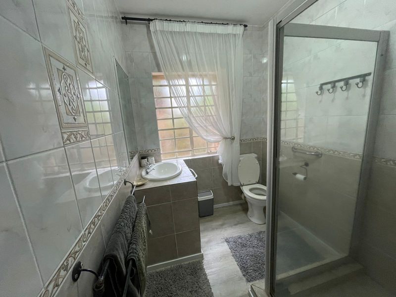 A functional bathroom featuring tiled walls, a vanity basin, a toilet, and a glass-enclosed shower.