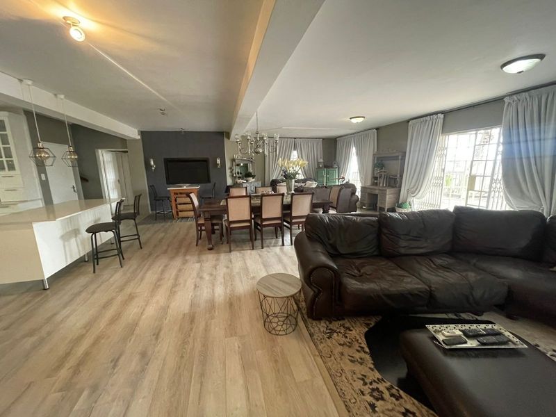 Spacious open-plan living area featuring a kitchen island, modern laminate flooring, and large sliding doors providing access to the exterior.