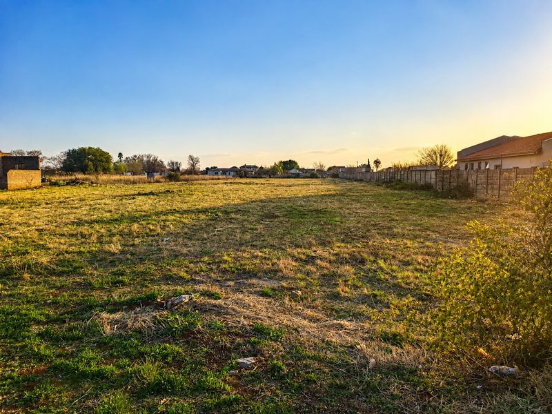 A vacant residential plot featuring open grass land and existing boundary walling, suitable for future development.