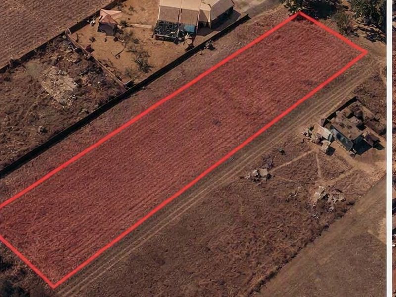 Aerial view of a vacant residential plot of land with boundary lines highlighted, situated in a developed residential area.