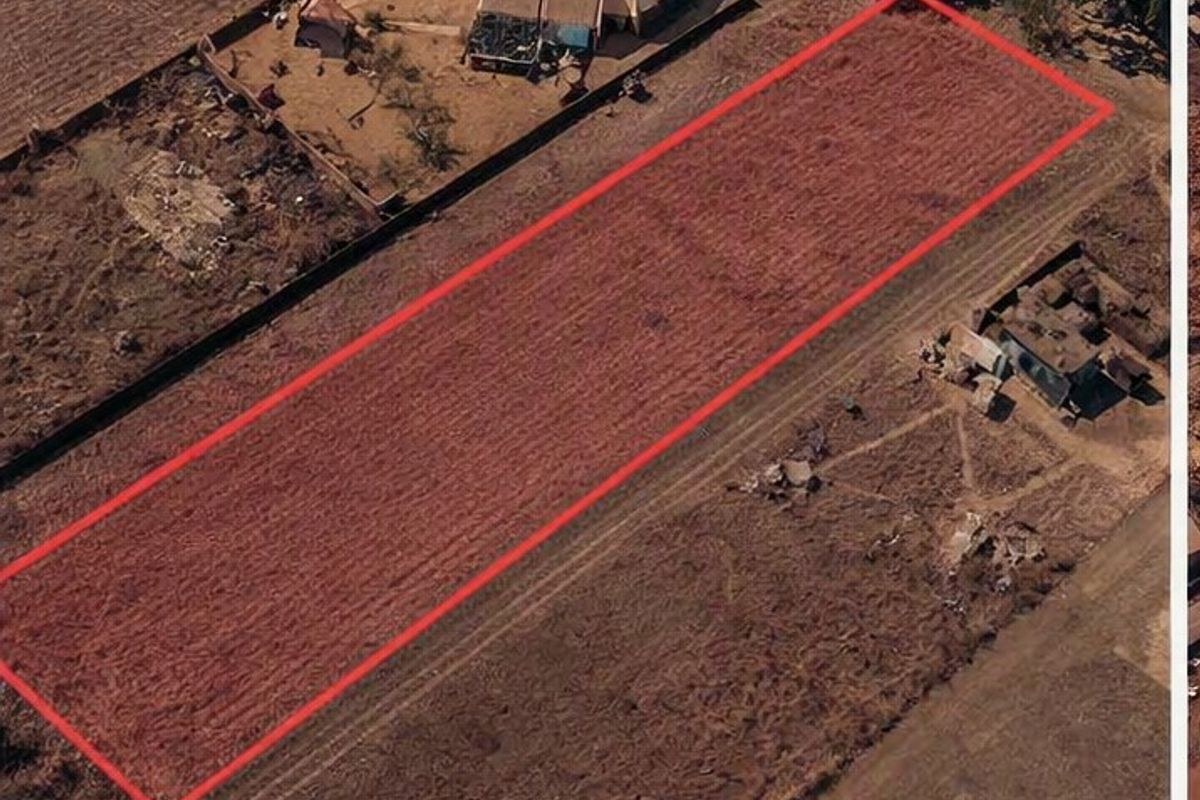 Aerial view of a vacant residential plot of land with boundary lines highlighted, situated in a developed residential area.