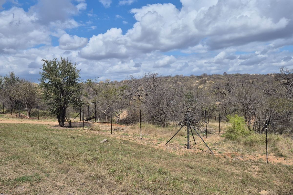 A view of the vacant residential land featuring established trees and perimeter electric fencing.
