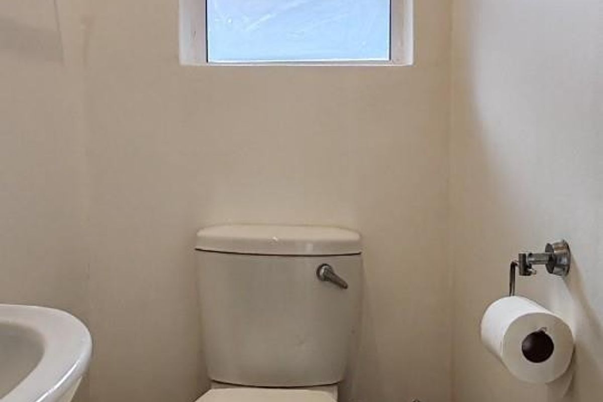 A functional bathroom featuring tiled flooring, a standard toilet, and a small casement window for natural light and ventilation.