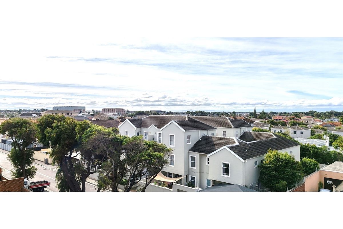 An elevated aerial view of the apartment complex, showcasing the building architecture, tiled roofing, and surrounding neighborhood landscape.