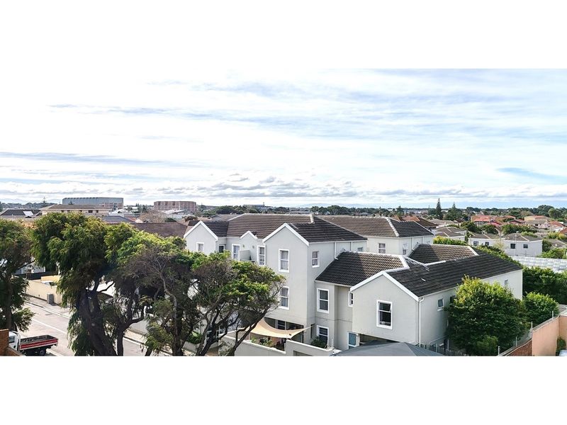 An elevated aerial view of the apartment complex, showcasing the building architecture, tiled roofing, and surrounding neighborhood landscape.