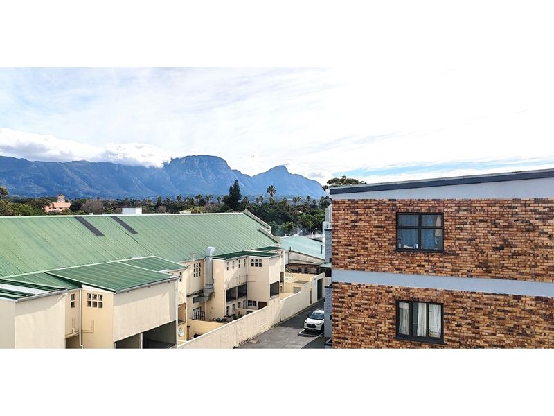 Elevated view overlooking neighbouring apartment buildings with a scenic mountain backdrop.