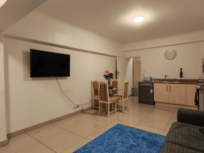 Open-plan living and kitchen area featuring tiled flooring, neutral cabinetry, and a functional layout suitable for modern apartment living.