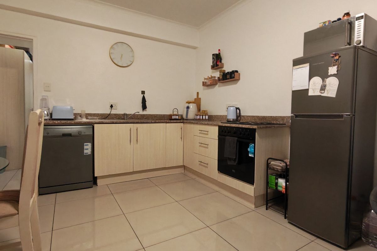 Functional kitchen featuring light wood-finish cabinetry, granite countertops, built-in oven, ceramic hob, and tiled flooring in an open-plan layout.