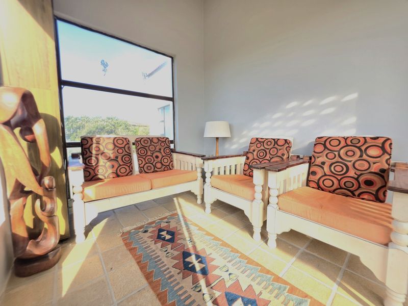 A sunlit patio area featuring tiled flooring and a large window, providing a bright and airy space for relaxation.