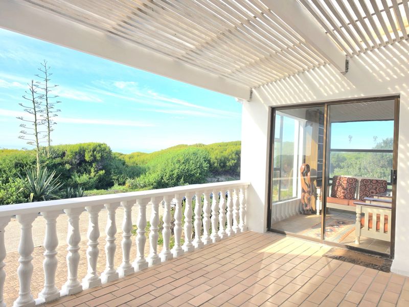 A covered patio featuring a slatted timber pergola, classic balustrade, and tiled flooring, offering a seamless transition to the outdoor garden area.