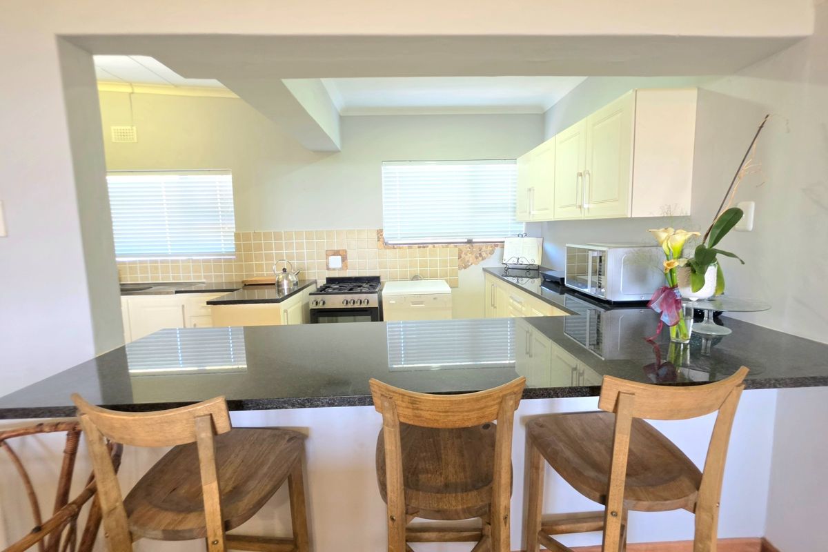 A functional kitchen featuring granite countertops, a breakfast bar, and a gas stove, with a tiled backsplash and ample built-in cabinetry.