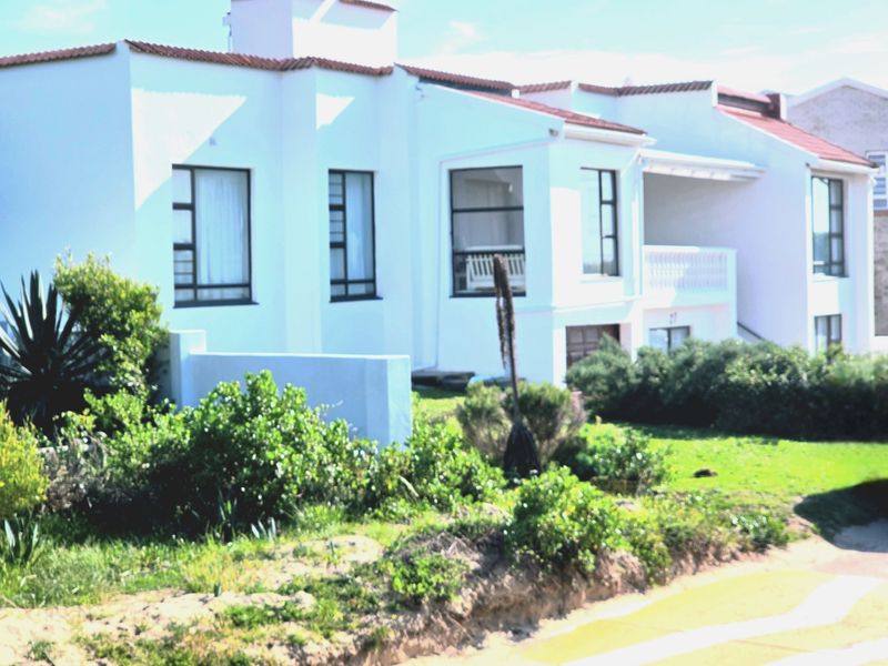 Front elevation of a white residential property featuring terracotta roof tiles, aluminium window frames, and a balcony, set within a landscaped garden area.