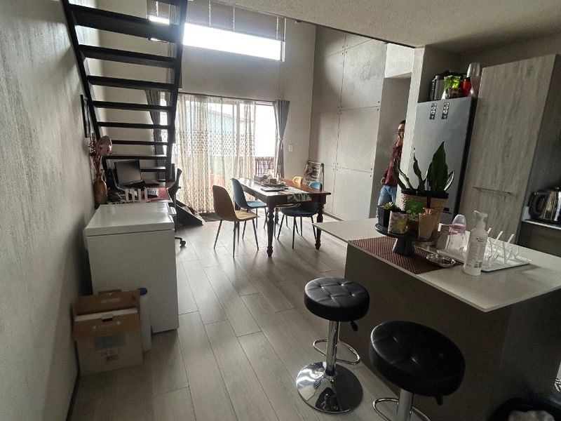 Open-plan living and kitchen area featuring modern laminate flooring, a central kitchen island, and a staircase leading to an upper level.