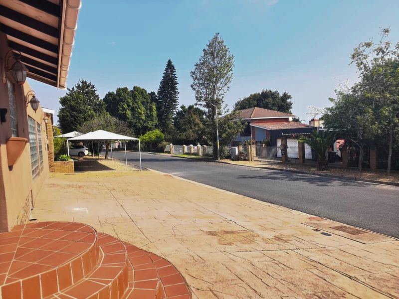 A street-level view showing the property entrance, paved driveway, and surrounding residential neighborhood context.