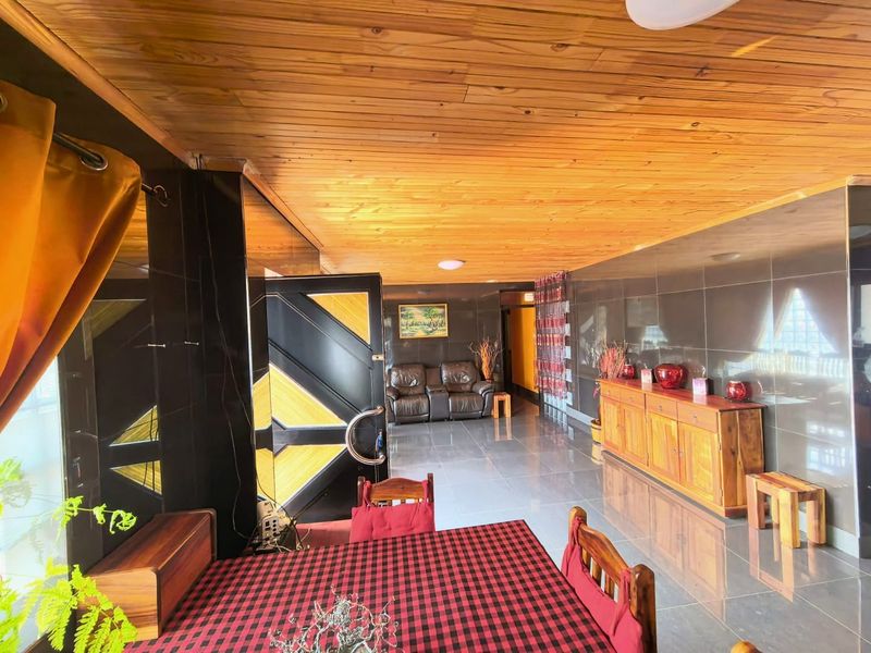 Spacious living area featuring a warm timber tongue and groove ceiling, glossy wall tiling, and large format floor tiles.