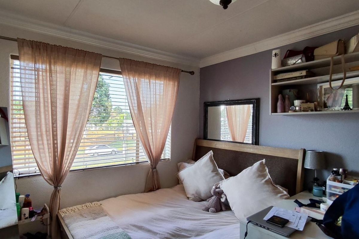 A cozy bedroom featuring built-in wall shelving, venetian blinds, and coving detail, offering a comfortable living space with natural light.