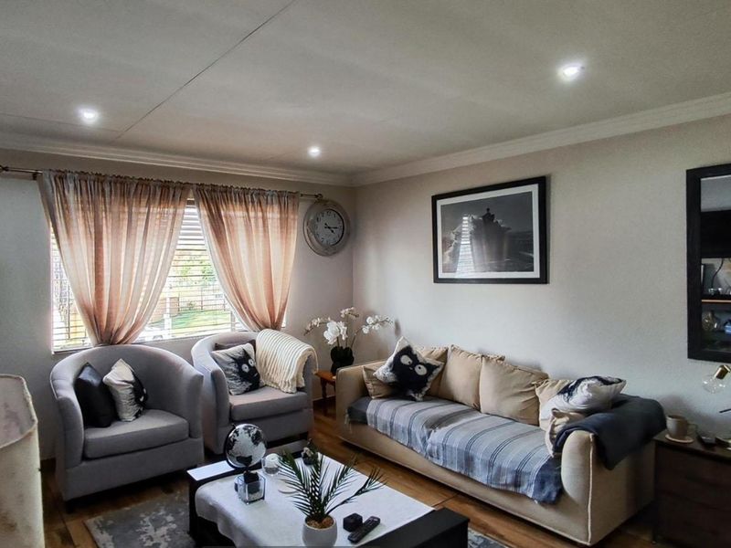 A comfortable living room featuring laminate flooring, recessed downlighting, and coved cornicing, creating a warm and inviting atmosphere for relaxation.