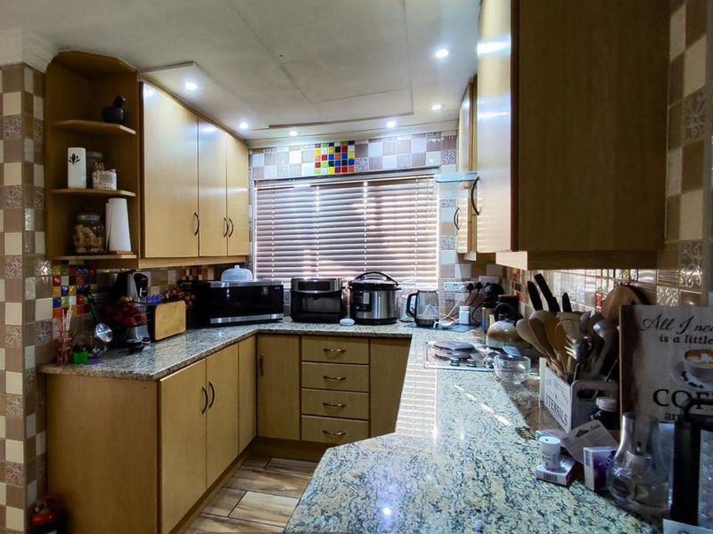A functional kitchen featuring granite countertops, laminate cabinetry, and a tiled backsplash with integrated lighting and a built-in hob.