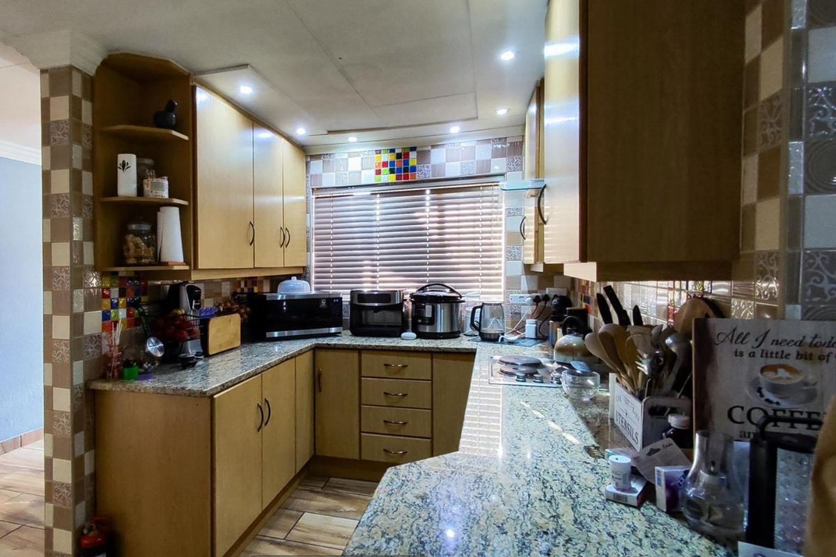 A functional kitchen featuring granite countertops, laminate cabinetry, and a tiled backsplash with integrated lighting and a built-in hob.