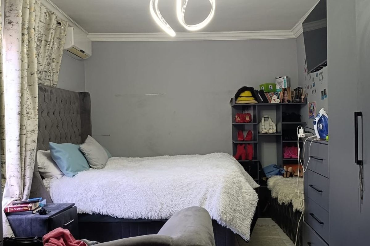 A bedroom featuring built-in cupboards, an air conditioning unit, and coving, providing a functional space with potential for cosmetic updates.