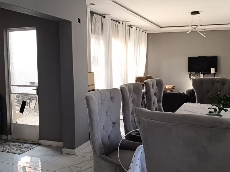 Spacious open-plan living and dining area featuring modern tiled flooring, recessed ceiling lighting, and large windows providing ample natural light.