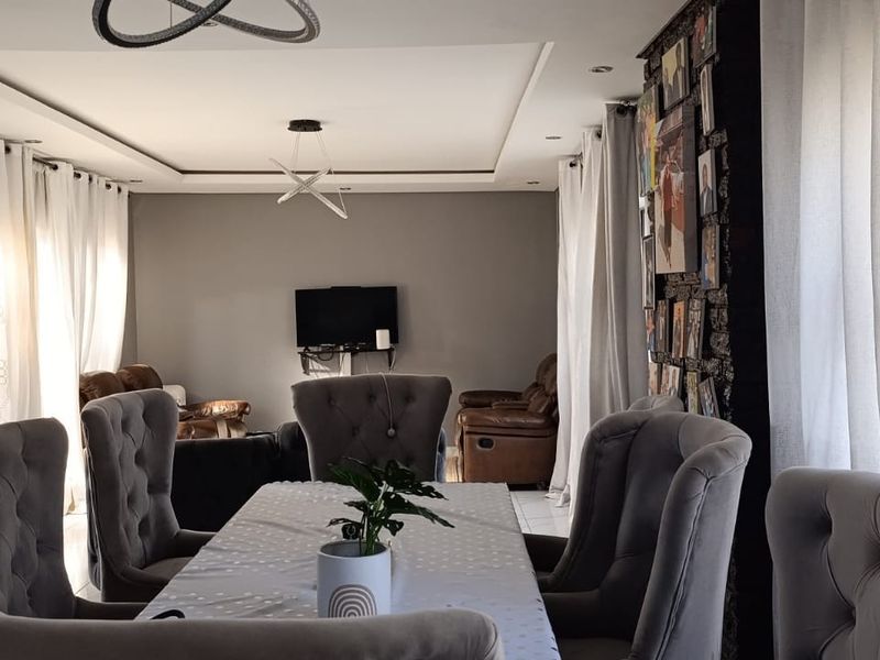 Spacious open-plan living and dining area featuring a textured stone feature wall, recessed ceiling lighting, and large sliding glass doors providing ample natural light.