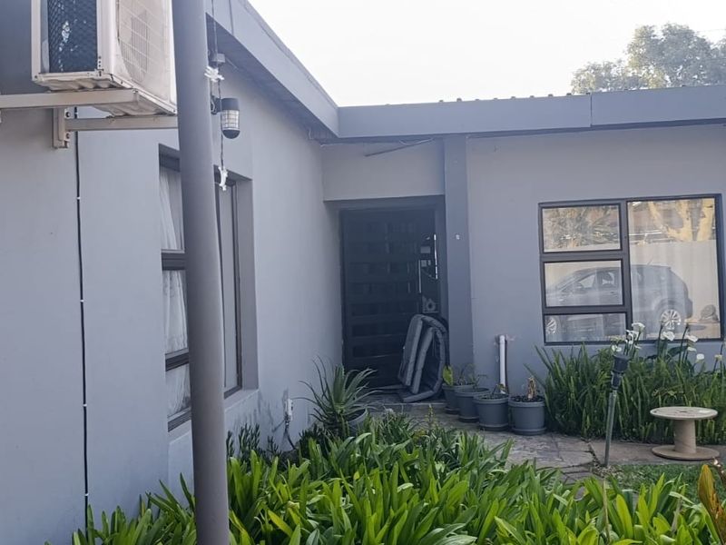 Rear exterior view of the property featuring grey painted walls, aluminium window frames, and an installed air conditioning unit.