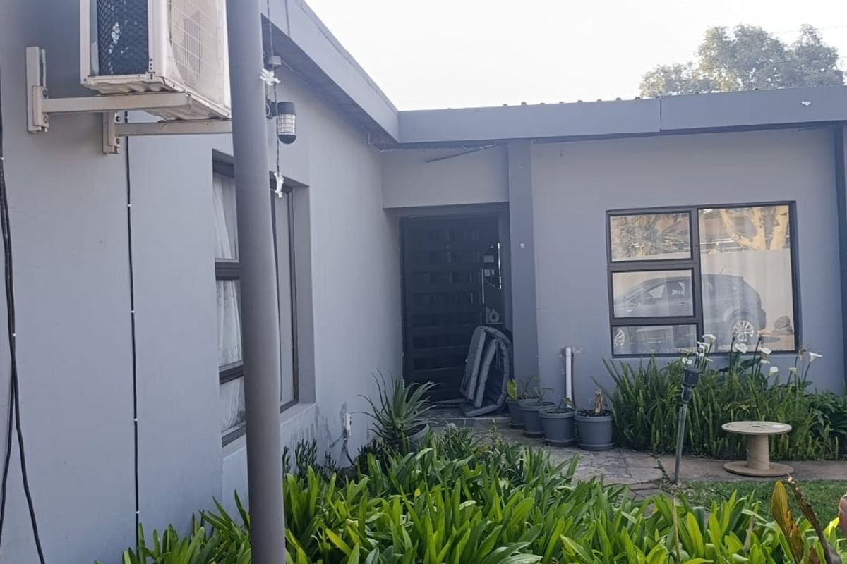 Rear exterior view of the property featuring grey painted walls, aluminium window frames, and an installed air conditioning unit.