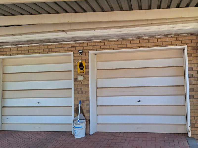 A double garage featuring brick exterior walls, corrugated metal roofing, and paved driveway access.