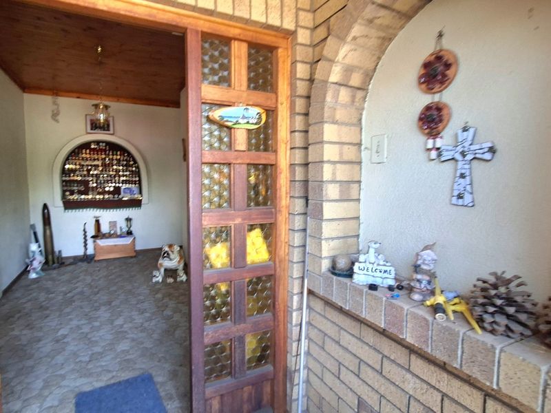 Entrance area featuring a brick archway, timber-framed glass door, stone flooring, and a built-in arched wall niche.