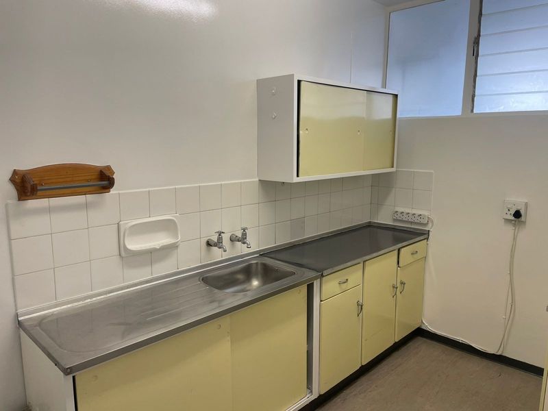 A functional laundry area featuring a stainless steel sink, tiled backsplash, and built-in cabinetry with ample storage space.