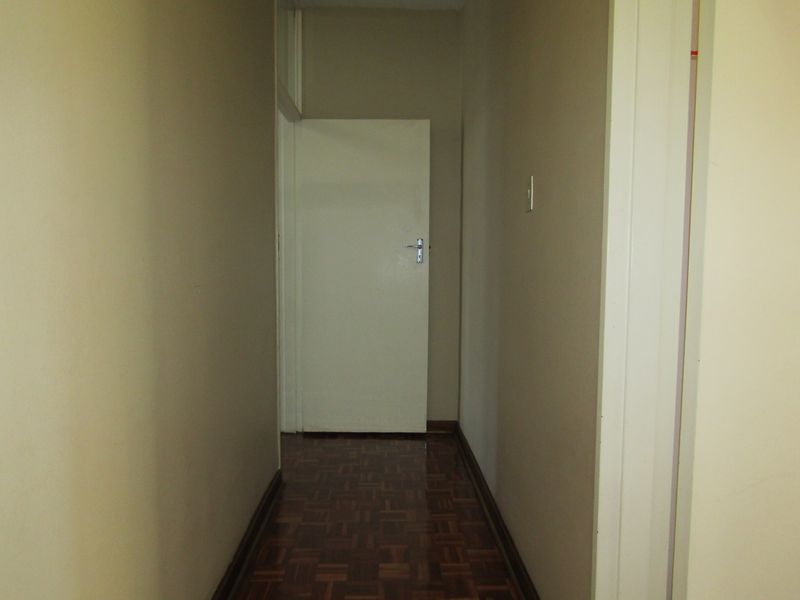 A narrow interior hallway featuring traditional parquet flooring and neutral wall finishes, providing access to adjacent rooms within the apartment.