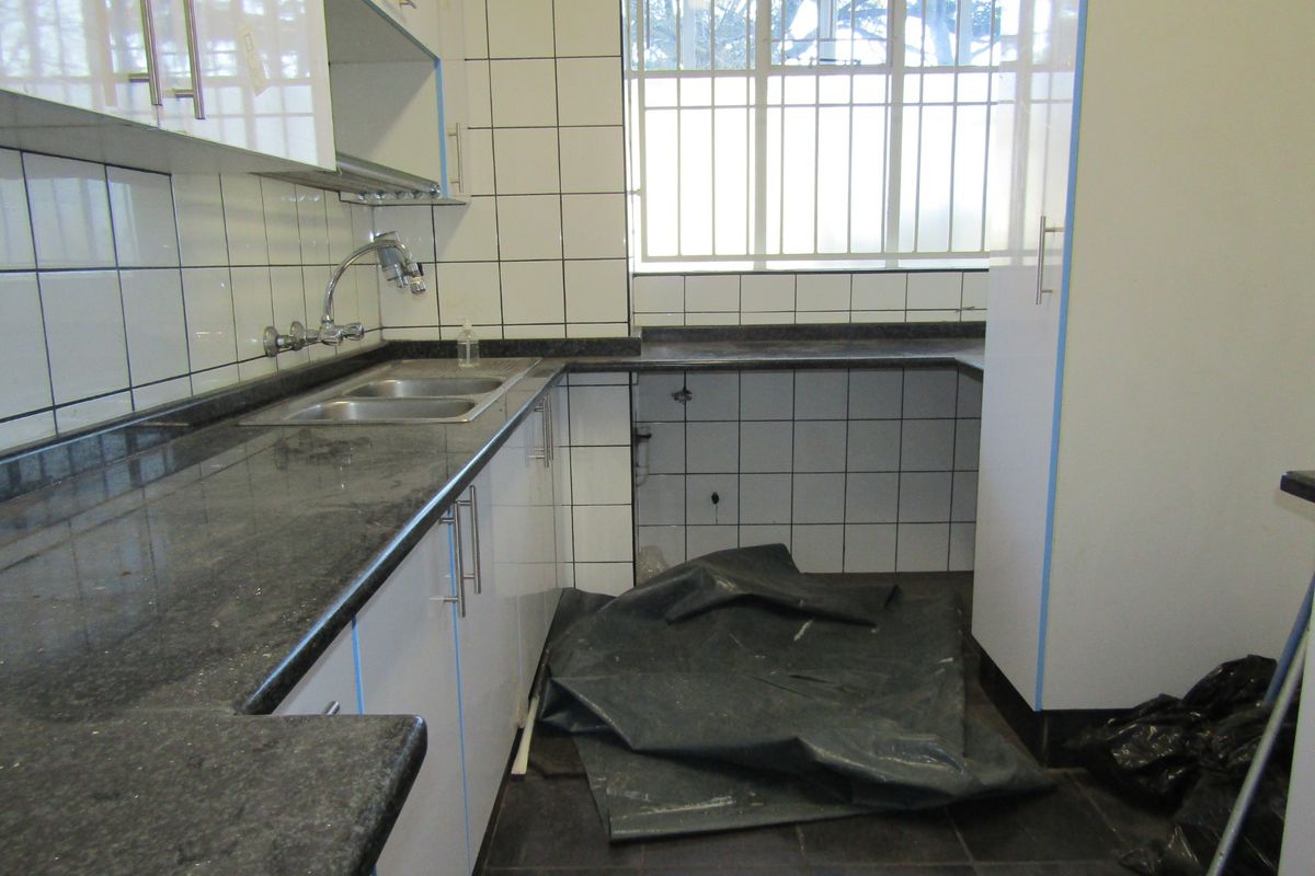A functional kitchen featuring granite countertops, white cabinetry, and tiled splashbacks, currently vacant and awaiting appliance installation.