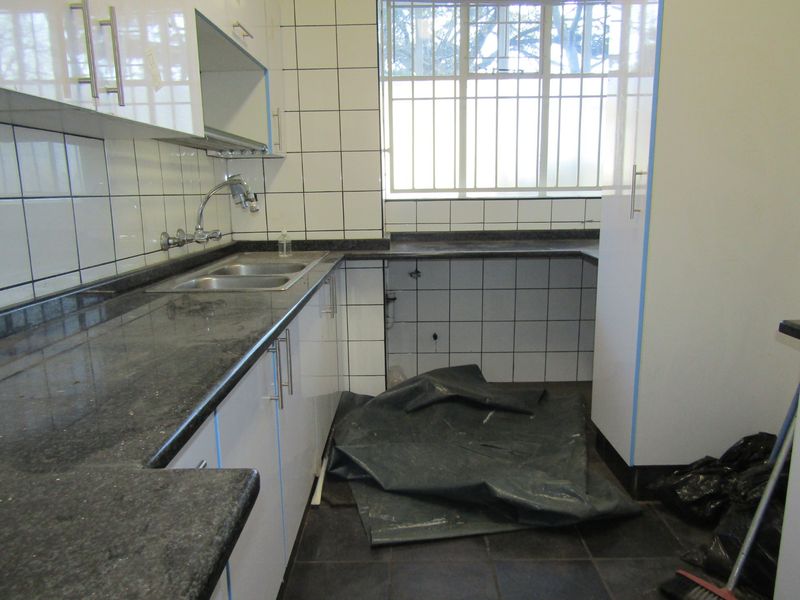 A functional kitchen featuring granite countertops, white cabinetry, and tiled splashbacks, currently vacant and awaiting appliance installation.