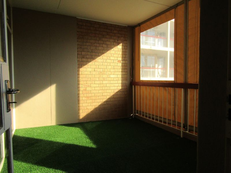 A covered balcony area featuring a brick accent wall, metal balustrade, and a retractable canvas screen for privacy.