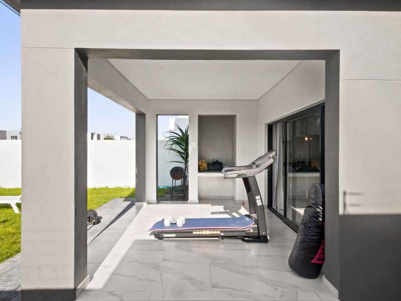 A modern covered patio featuring large format floor tiles, recessed lighting, and seamless access to the interior through sliding glass doors.