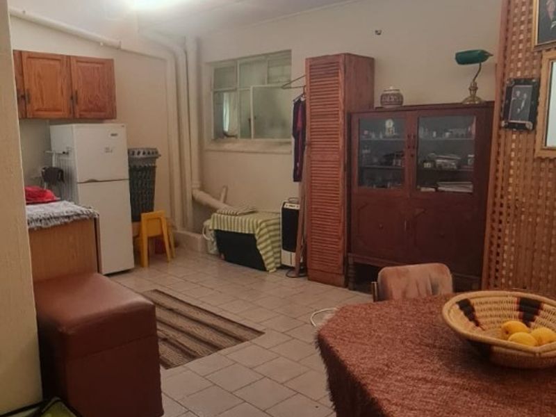 A dated kitchen area featuring tiled flooring, wooden cabinetry, and high-level clerestory windows, offering potential for a modern renovation.