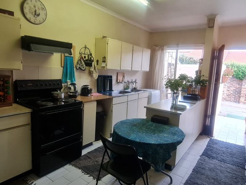 A functional kitchen featuring built-in cabinetry, an electric stove with extractor fan, and direct access to an outdoor patio area.
