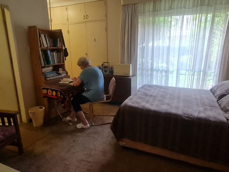 A bedroom featuring built-in cupboards, carpeted flooring, and a large window allowing natural light.