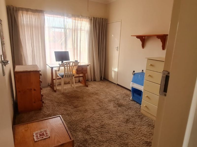 A bedroom featuring carpeted flooring, a built-in cupboard, and large windows with curtain rails, offering a functional space ready for updates.