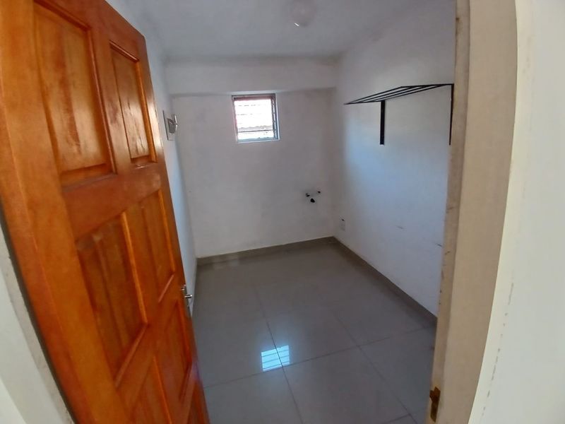 A functional, empty laundry room featuring tiled flooring, a wall-mounted drying rack, and dedicated plumbing connections for laundry appliances.