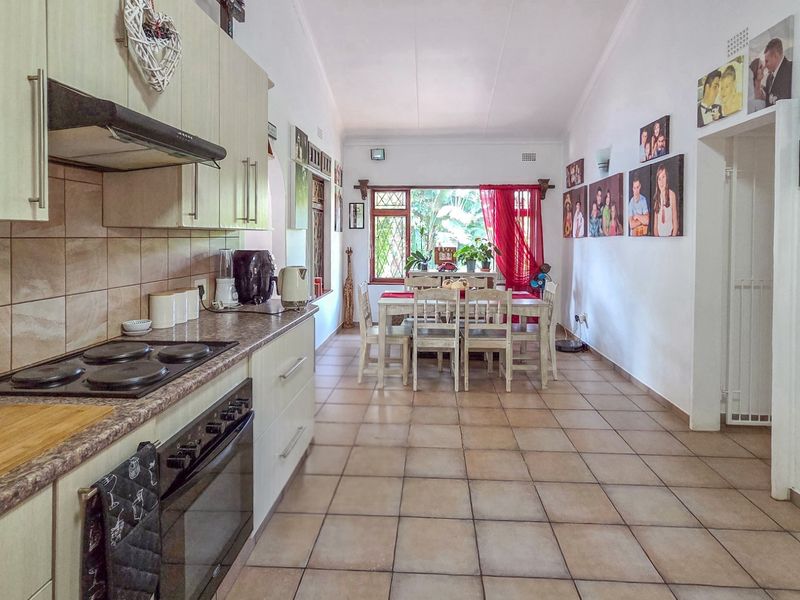 Open-plan kitchen and dining area featuring tiled flooring, built-in cabinetry, and integrated cooking appliances, creating a functional and connected living space.
