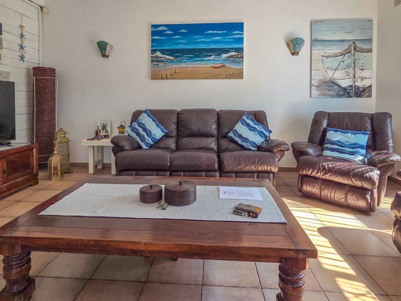 A comfortable living room featuring tiled flooring and wall-mounted lighting fixtures, providing a functional and inviting space for relaxation.