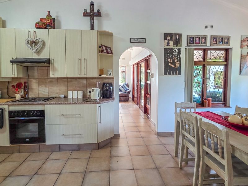 Open-plan kitchen and dining area featuring tiled flooring, built-in cabinetry, and an arched transition to the living space.